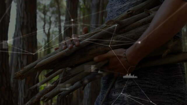 Man carrying dry branch bundle in pine forest, overlaying network lines and data points for tech