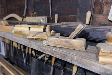 Woodworking tools displayed on a rustic shelf in a traditional workshop