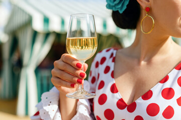 Woman in a red flamenco dress holding a glass of fino sherry (manzanilla sherry) during Seville April Fair celebration