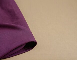 Close-up of a folded purple fabric draped over a beige background, showcasing texture and color contrast.