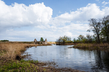 Immerse yourself in a serene riverside landscape featuring rustic ruins set against a partially cloudy sky, perfect for exploration and peaceful outdoor moments amidst natures beauty