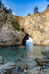 Natural rock arch frames tranquil blue waters on a sunny day by the coastline