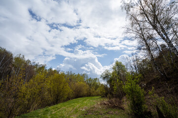 A stunning scenic view of an expansive lush green landscape unfolds beneath a partly cloudy sky, inviting exploration and adventure in its breathtaking beauty and tranquil surroundings