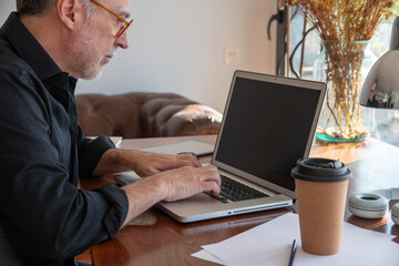 Man Working on Laptop at Desk with Coffee