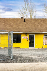 Yellow Construction Site Office Building With Gravel Path and Chain-Link Fence