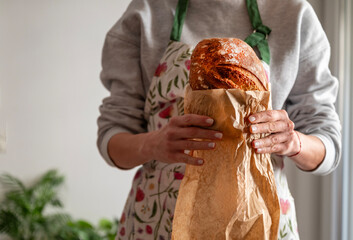 Woman holding freshly baked sourdough bread  