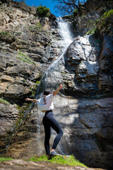 Young woman standing in front of a spring waterfall
