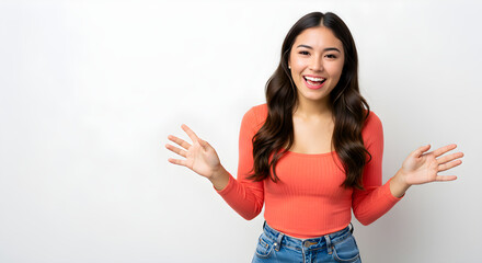 A cheerful woman in a vibrant orange top and jeans, smiling and gesturing with open hands against a white background.