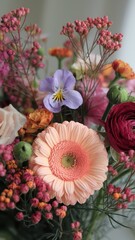 Peach gerbera with asters, ranunculus, roses, and tiny red accents