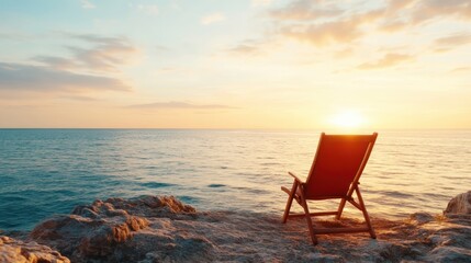 A calming scene of a chair positioned on rocky ground by the sea, with soft waves lapping against the shore under a beautiful sunset, inviting viewers to unwind and reflect.