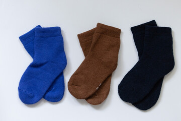 Three pairs of warm socks on a white background, blue, brown, black