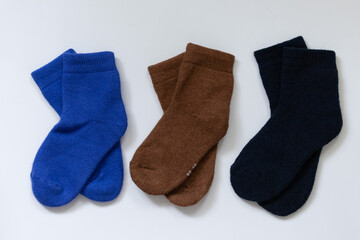Three pairs of warm socks on a white background, blue, brown, black