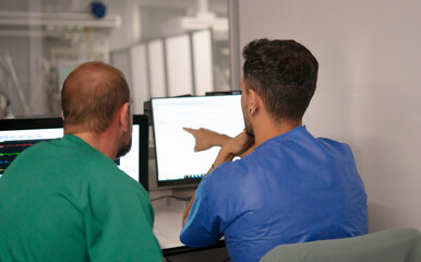 Medical team analyzing data on computer screens in hospital control room