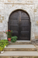 Brown painted wooden door in an arched doorway in a stone building.