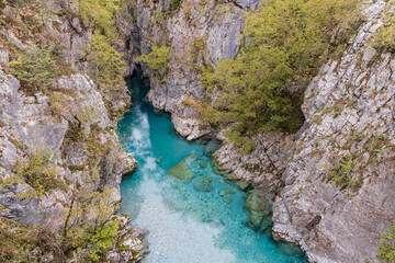 Clear aque blue water of the Valbonas River in a rocky canyon.