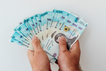 Holding a fan of banknotes with close up of hands and Ukrainian currency displayed prominently