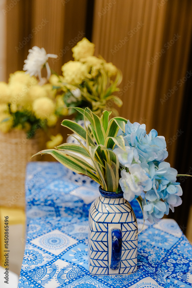 Poster floral arrangement in a patterned vase on a matching tablecloth creating a cohesive and charming dis