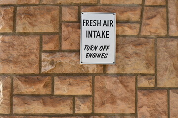 Fresh air intake sign on stone building. Please turn engine off.