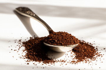 Old spoon with ground coffee in sunlight, aroma of the beginning of the day