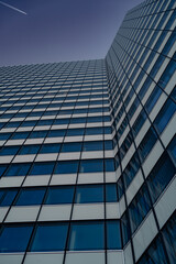 A modern building reflects the sky with its geometric glass facade.