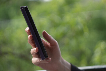 A woman's hands using a mobile phone outdoors, close-up with copy space