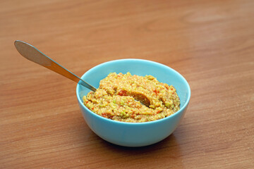 blue ceramic bowl filled with fresh guacamole and a metal spoon, ready for serving as a vibrant and healthy dip