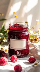 Jar of raspberry jam with fresh berries and wildflowers in sunlight