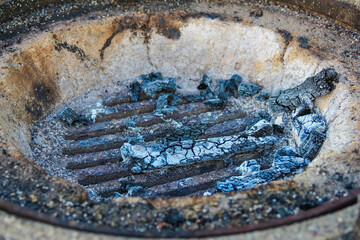 Oval fire pit with burnt logs and ashes showing remains of outdoor campfire cooking session