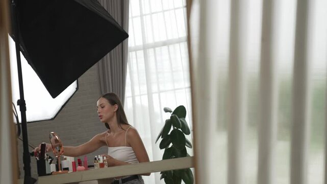 Young beautiful woman making with cosmetic makeup doing hairstyle tutorial video content for social media. Beauty blogger smile to camera while showing how to beauty care to audience or follower. Adit