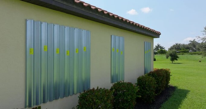 Steel sheets mounted as storm shutters for hurricane protection of house windows. Protective measures before natural disaster in Florida