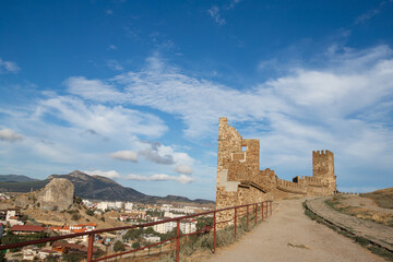 a ruined historical ancient fortress stands against the backdrop of a modern city
