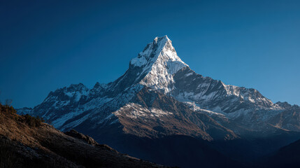 Fototapeta premium The majestic snow-capped mountain peak glistens under the bright blue sky, creating a breathtaking natural landscape for adventurers and nature lovers alike.