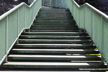 Old metal stair bridge. Urban pedestrian passage. Green structure with peeling paint. Industrial...
