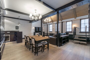 Modern interior of a spacious living room. Stylish design in urban style. Upholstered sofas and a table with chairs..