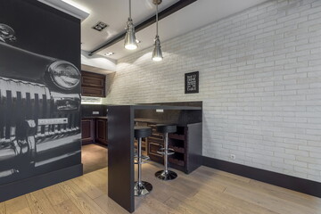 Stylish interior of the kitchen in an urban style. White brick wall. Hanging lamps above the table,...
