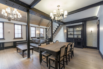 The unique interior of the living room in the townhouse. White walls, black beams. A dining table and a seating area with a sofa.