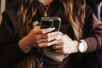 Woman using smartphone. Stylish hands closeup. Blue manicure and rings. Casual fashion accessories. Mobile communication. Social media browsing background. Modern lifestyle. Everyday digital routine.