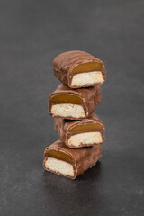 Chocolate bar with caramel and cookie. Dark background. Close-up