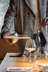 Champagne tasting, The sommelier pours sparkling wine from the decanter into a beautiful glass,...
