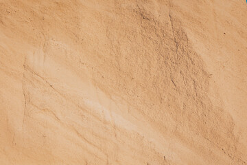 Golden grains of clay or sand stretch endlessly under a bright sun, creating a serene desert landscape in the midday glow