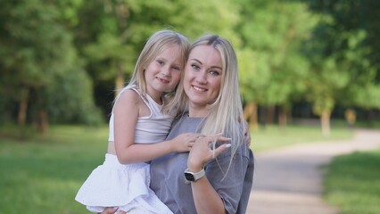 Naklejka premium A heartwarming scene of a loving mother gently holding her daughter, both surrounded by vibrant and lush greenery