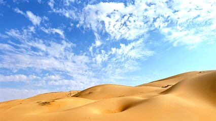 Golden sand dunes undulating across desert landscape, casting intricate shadows beneath expansive...