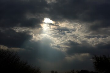 Fototapeta premium Sunlight streaming between grey clouds view 