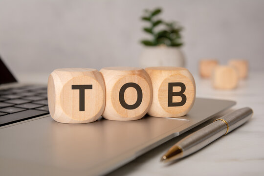 Wooden cubes with TOB acronym on laptop keyboard.