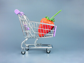 Large ripe strawberries in a shopping trolley, close-up. Buying berries and food at the supermarket, grocery basket.