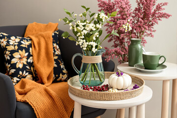 white flowers in teal pitcher on woven tray with autumn decor