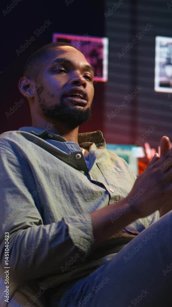 Poster vertical video african american person smiling and chatting during a video call at home, sharing ins