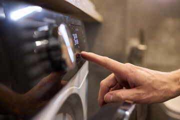 Individual Interacting with a Modern Washing Machines Control Panel for Efficient Laundry Tasks