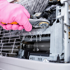 gloved hand using a cleaning tool to meticulously wipe the internal components of a machine
