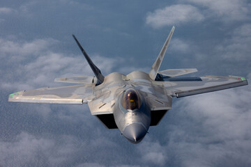 Frontal view of a a F-22 Raptor  flying over the Pacific ocean and a cloud layer 
